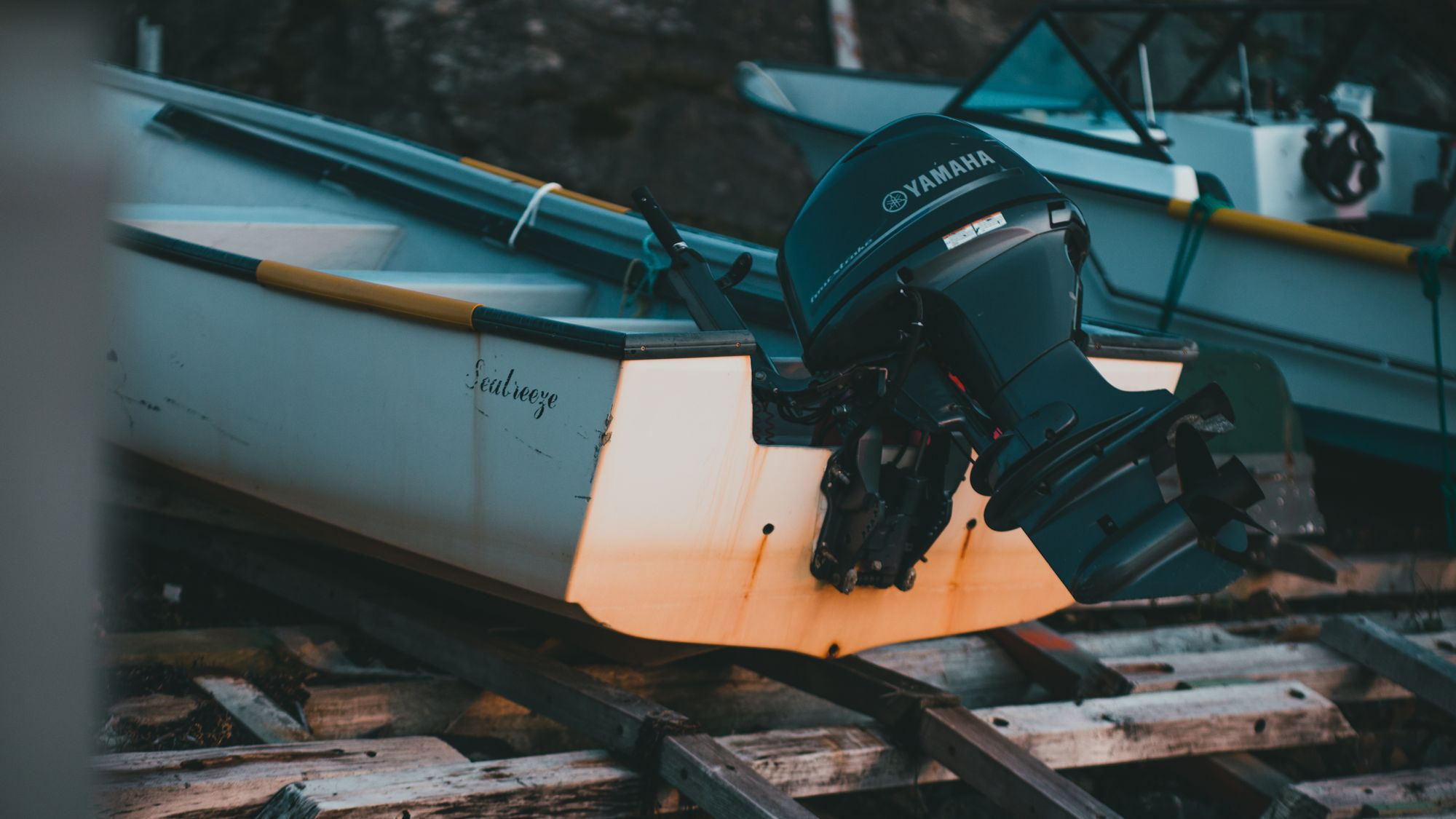 A boat on a trailer at a ramp with an outboard motor tilted up.